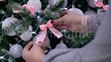 年轻女子的双手在圣诞树上<strong>展</strong>开一个蝴蝶结，用节日的<strong>灯光</strong>和